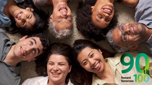 A diverse group of people gathering with smiles, lying down and looking up.